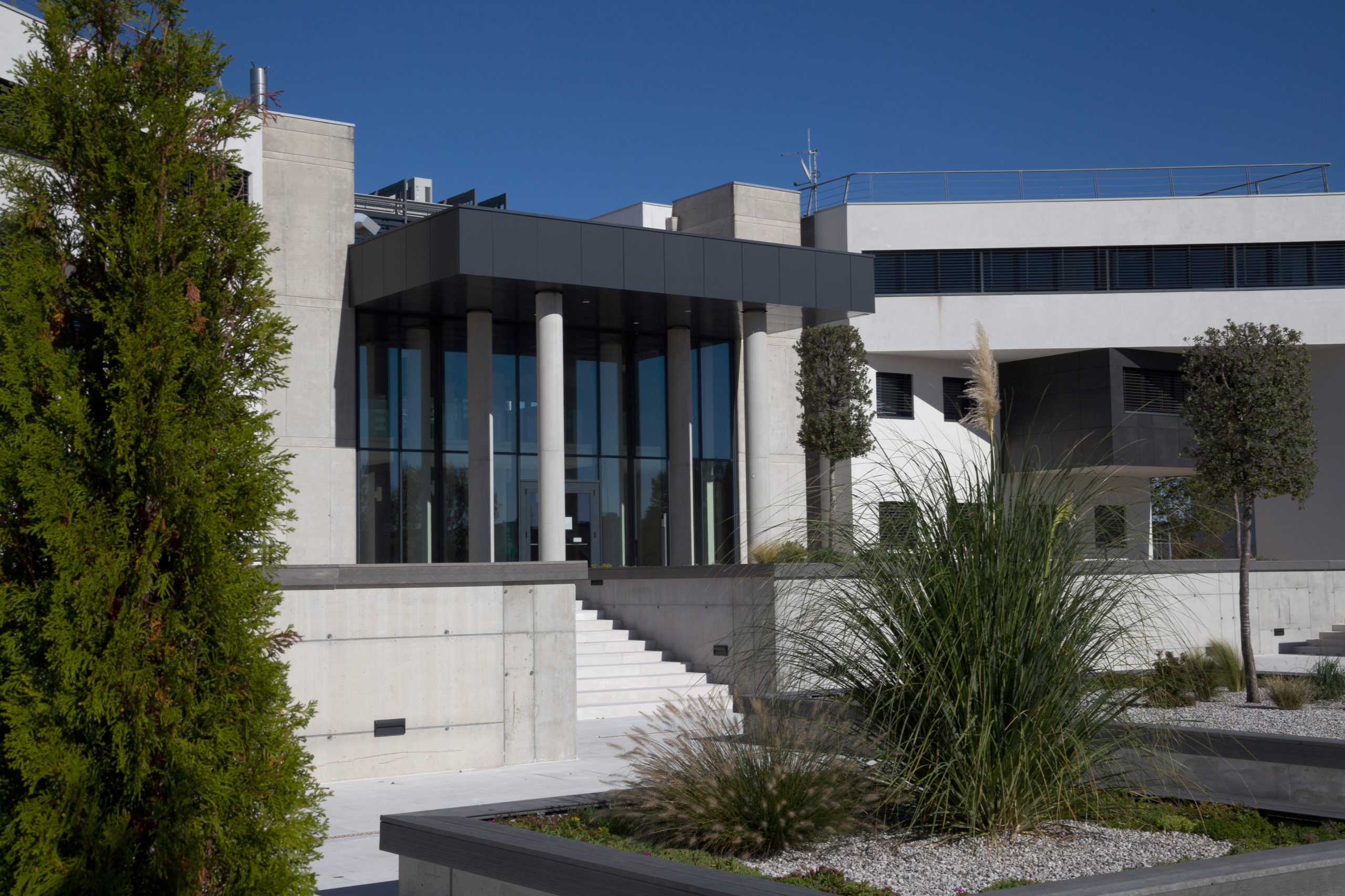 Eingang eines Gebäudes im Güterverkehrszentrum Pordenone mit Säulenvorbau, Treppe und Beeten